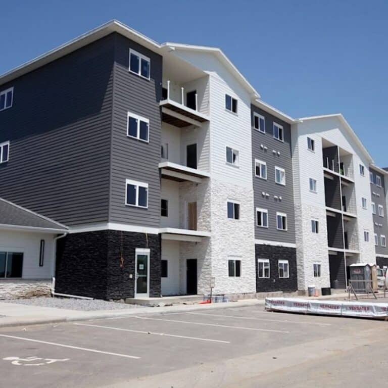 A multi-story apartment building with clean siding, balconies, and a freshly maintained exterior, showcasing the results of professional commercial pressure washing services.